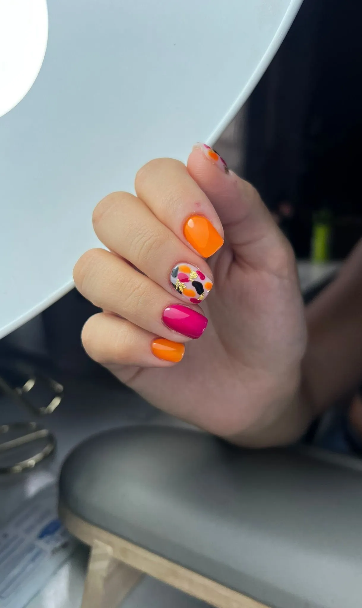 Manicura corta en naranja y fucsia con diseño abstracto
